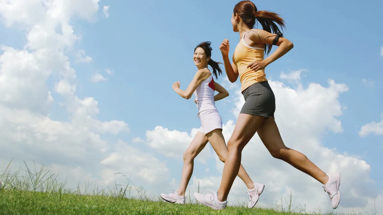 Two women running across a grassy hill