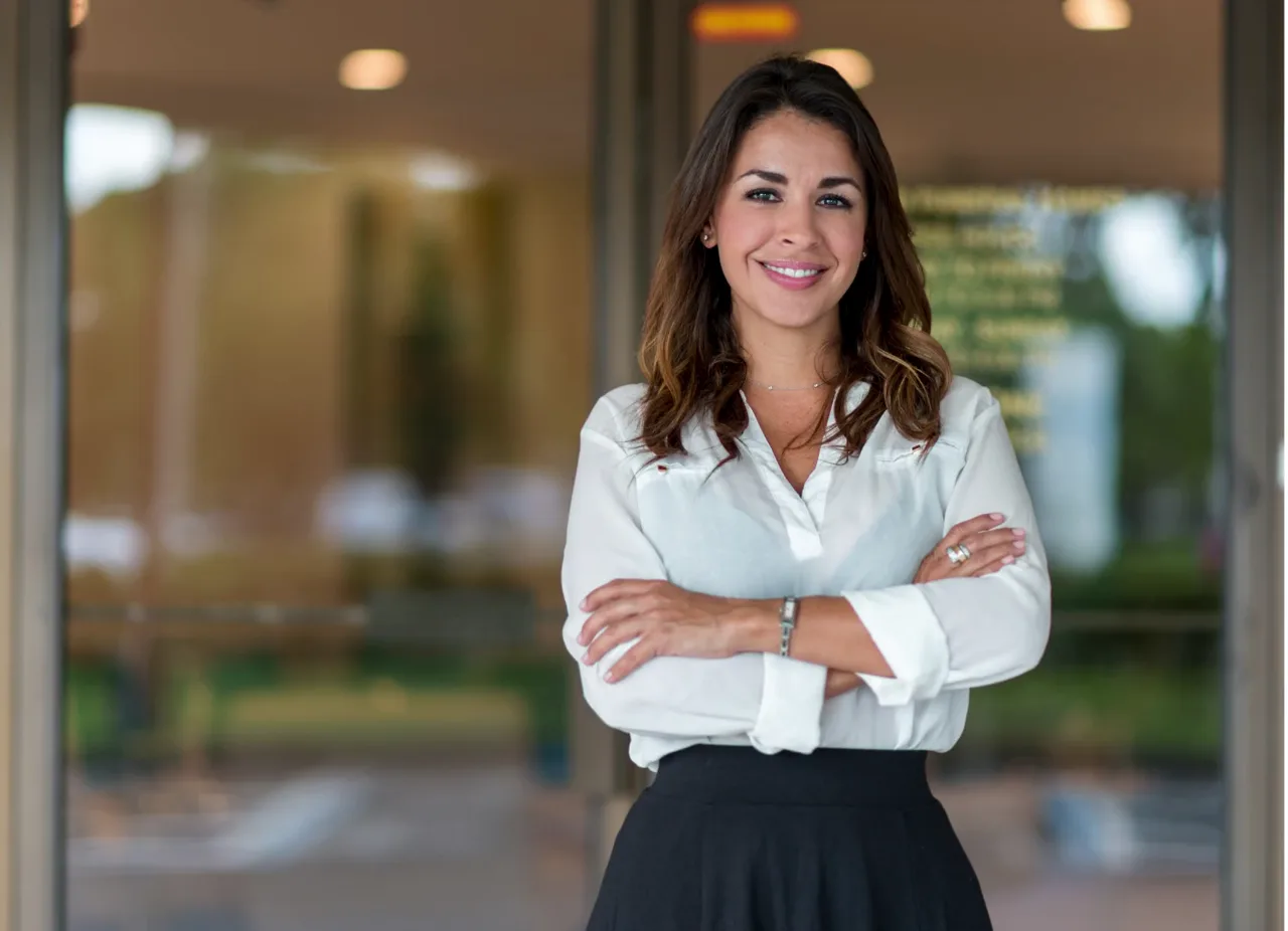 A smiling professional woman standing with her arms crossed