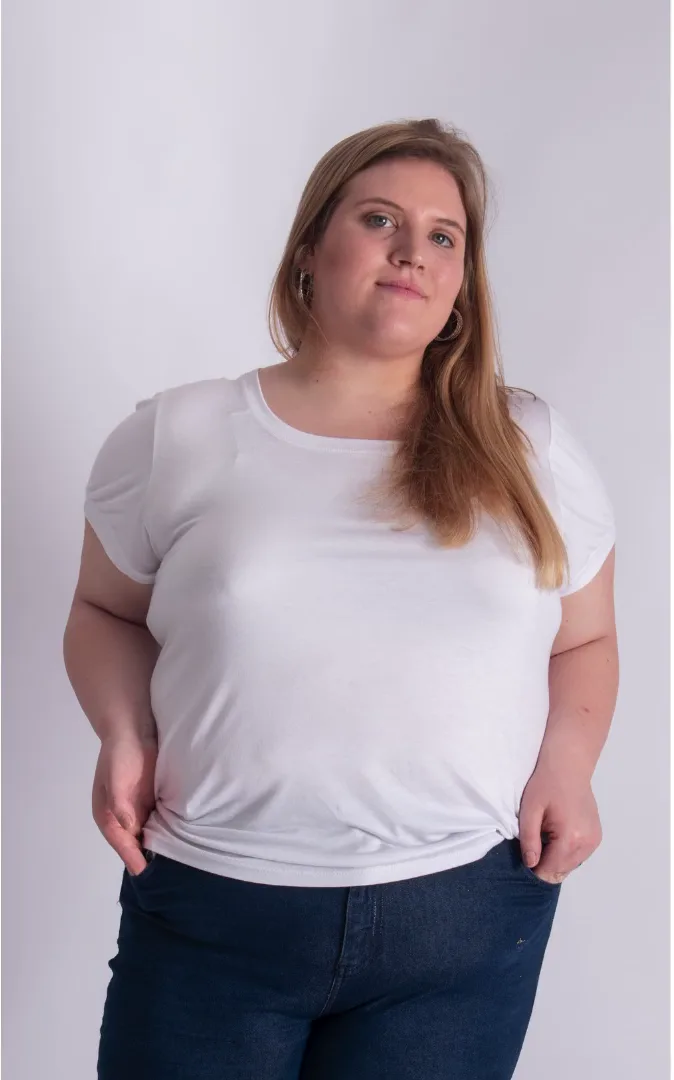 A woman in a white T-shirt standing against a light wall